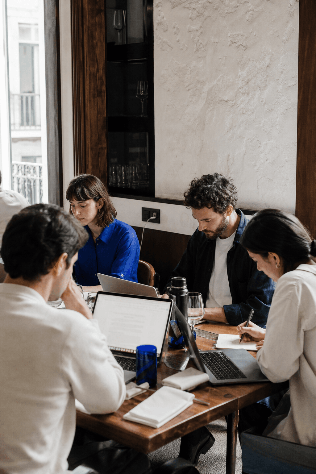 Remote workers working together at a long table in a bright restaurant